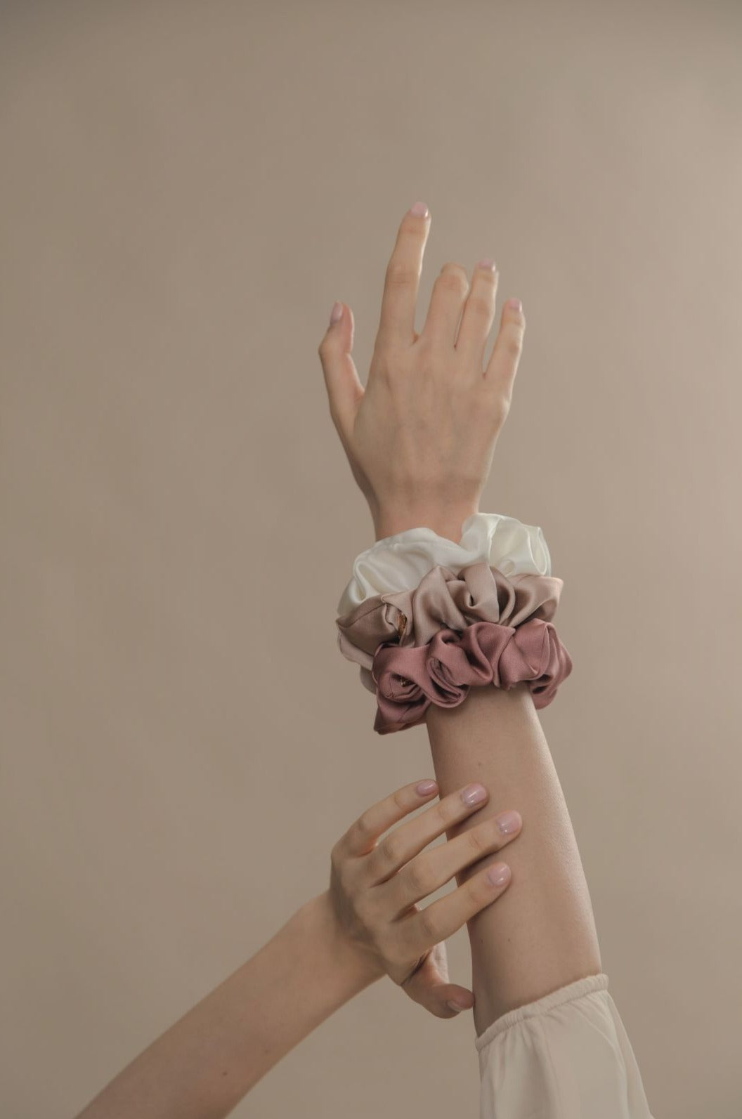 Model's hand with Modern lux hair jewelry ONLY REAL SILK Scrunchies in Pink, Champagne and white color 